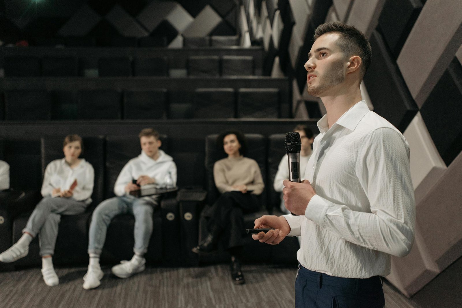 A young man delivers a presentation to a small group in a modern conference room.